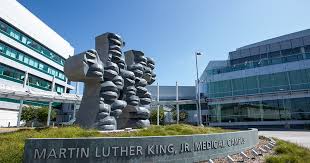 A modern medical facility with a prominent sculpture of abstract figures in front, labeled 